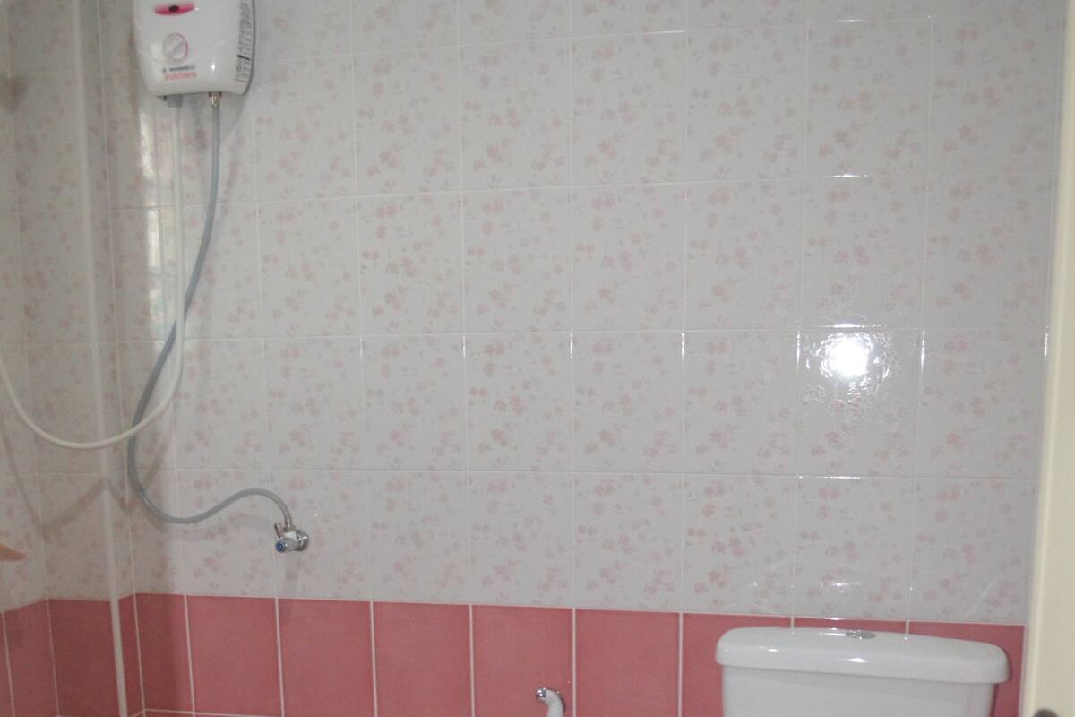Une salle de bain équipée de toilettes, d’une douche et d’un sèche-mains.
