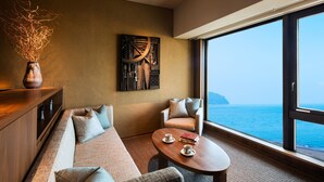 A modern room with a large window, a sofa, a table, and a decorative wall piece. - Hoshino Resorts KAI Anjin (Ito)