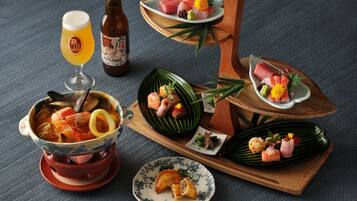 A variety of Japanese dishes including sushi, sashimi, and a bowl of seafood stew, served on wooden trays and plates.