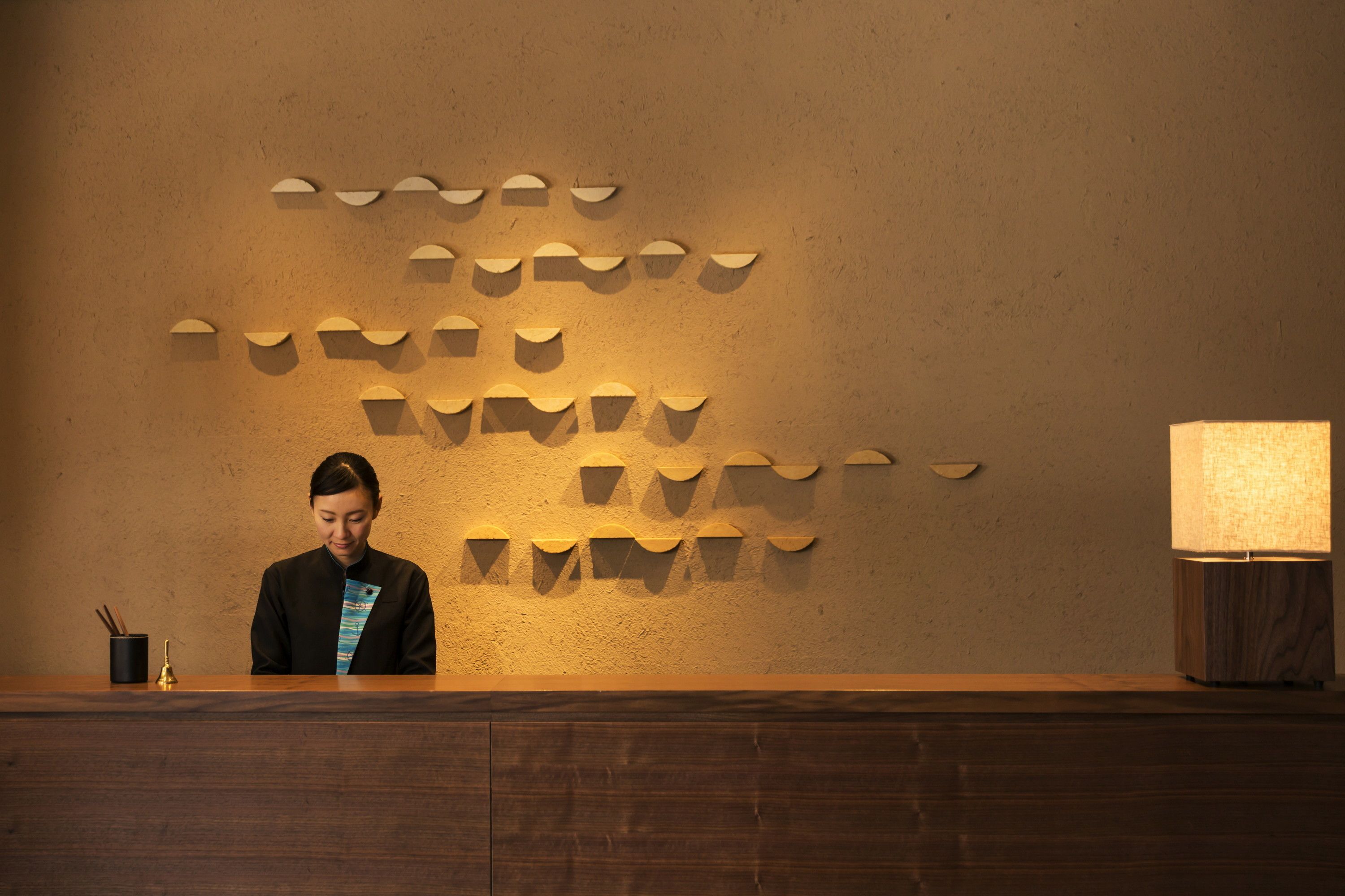 A reception desk with a wooden surface and a wall-mounted light fixture.