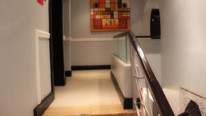 Ein Flur mit Fliesenboden, einer Holzhandläufe und einem an der Wand befestigten Kunstwerk.