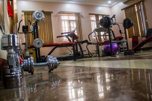 Uma academia com diversos equipamentos de exercício, incluindo halteres, barras e uma bicicleta ergométrica.