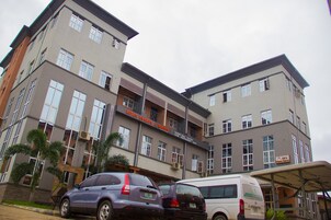 Um edifício de vários andares com varandas, um letreiro com 'Rita's Events & Suites' e carros estacionados.