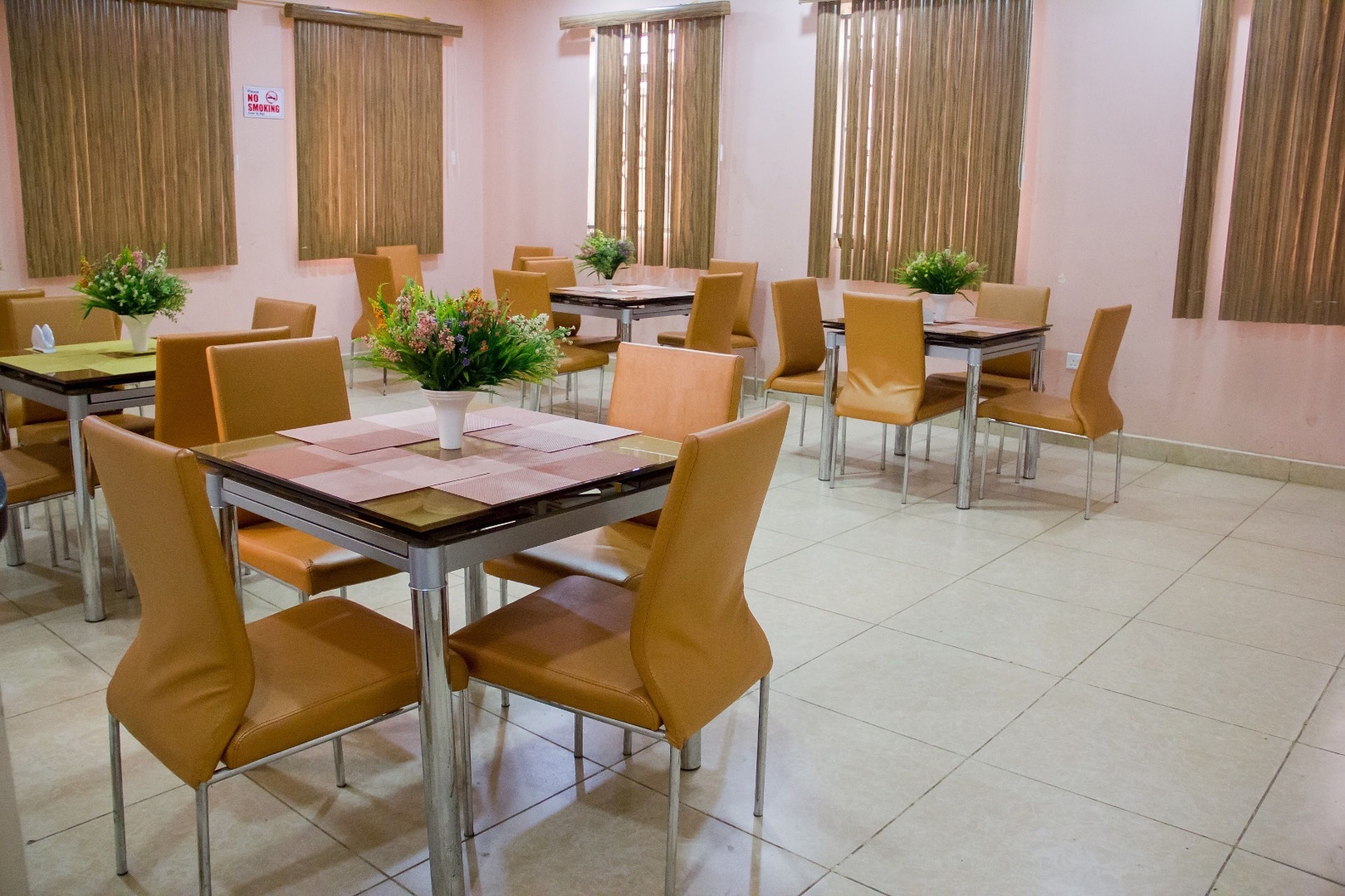 Un comedor con varias mesas y sillas, cada una con una pequeña planta encima.