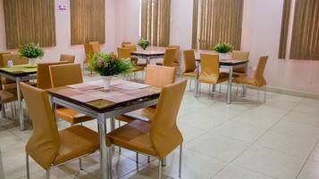 Un comedor con varias mesas y sillas, cada una con una pequeña planta encima.