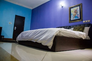 Um quarto com uma cama, uma porta e uma parede com um quadro emoldurado.
