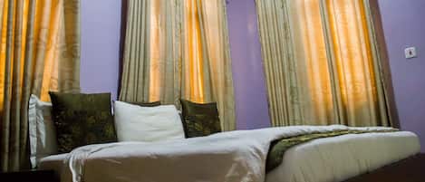 A bedroom with a bed, pillows, and curtains.