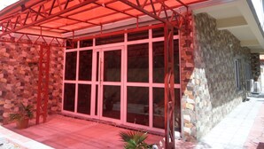 A building with a red metal awning, large glass windows, and a stone facade. - The Venetian Suites (Abuja)