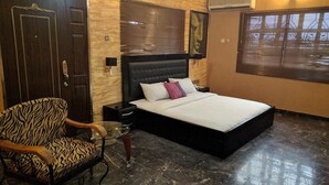 A bedroom with a bed, a chair, a nightstand, and a wall-mounted air conditioner. - Porschester Hotel and Suite (Lagos)