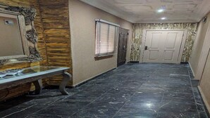 A hallway with a marble floor, a bench, a door, and a window with blinds. - Porschester Hotel and Suite (Lagos)