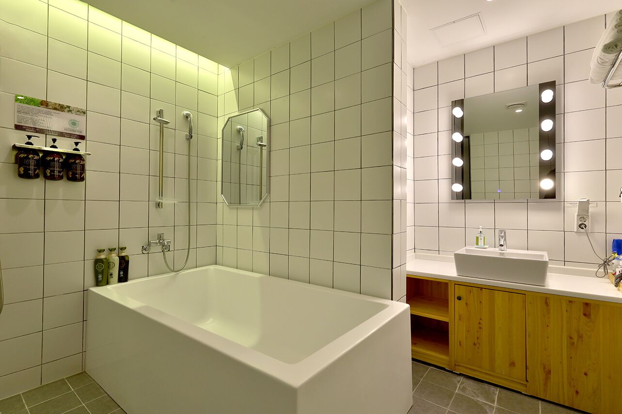 A modern bathroom with a large bathtub, a shower, and a vanity with a mirror.
