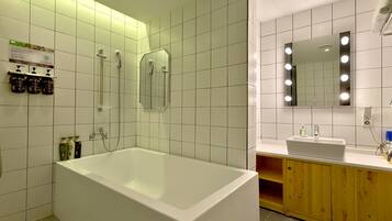 A modern bathroom with a large bathtub, a shower, and a vanity with a mirror.