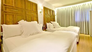 A hotel room with two beds, wooden headboards, and a large window with curtains. - February Hotel Sungseo (Daegu)