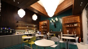 A modern restaurant with wooden accents, green patterned flooring, and white and yellow chairs. - February Hotel Sungseo (Daegu)