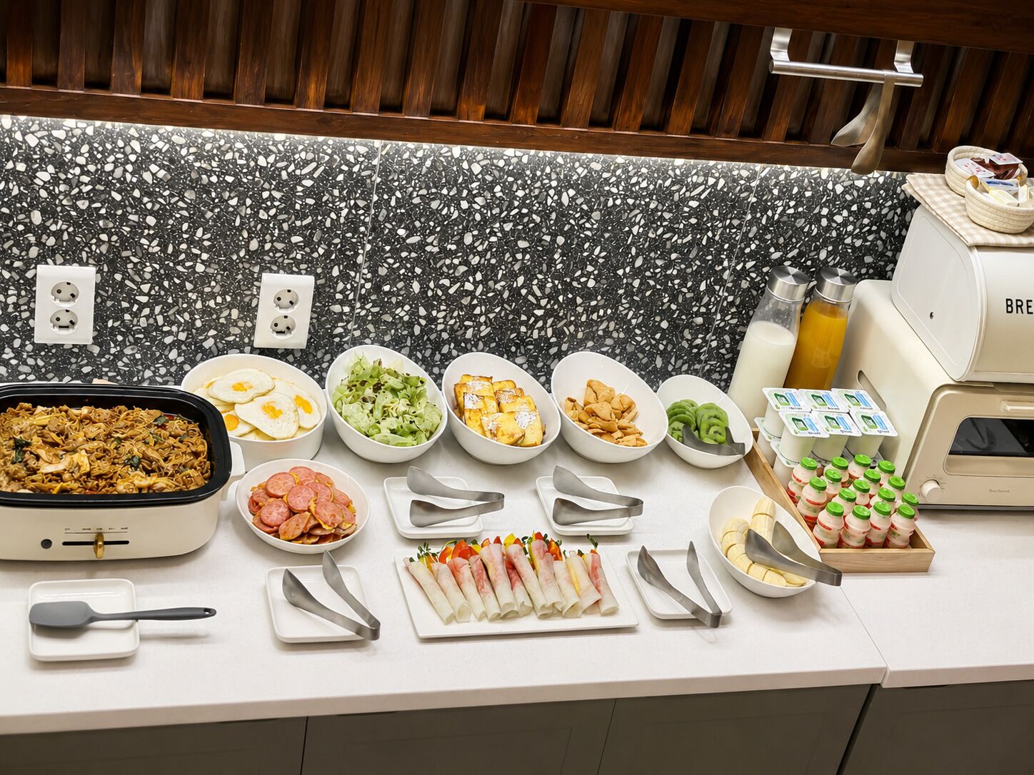 A buffet setup with various food items and utensils.