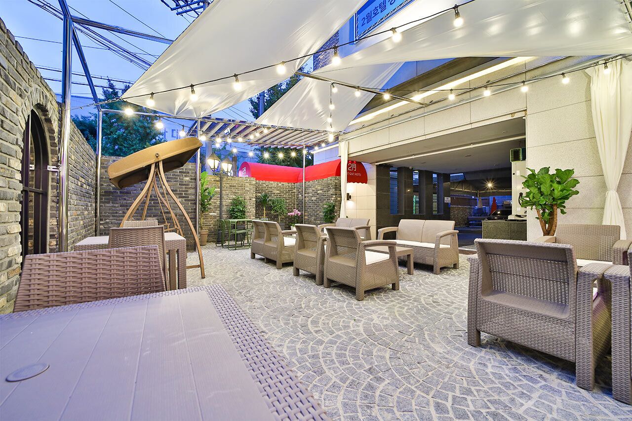 Un patio al aire libre con mobiliario de mimbre, un telescopio y luces colgantes.