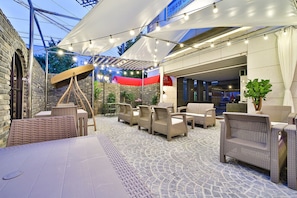 An outdoor patio area with wicker furniture, a telescope, and string lights.