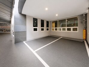 Un vaste espace intérieur doté d’un sol gris, de murs blancs et de nombreuses fenêtres.