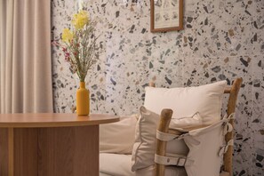 A wooden table with a vase of flowers, a chair with a cushion, and a terrazzo floor. - February Hotel Sungseo (Daegu)