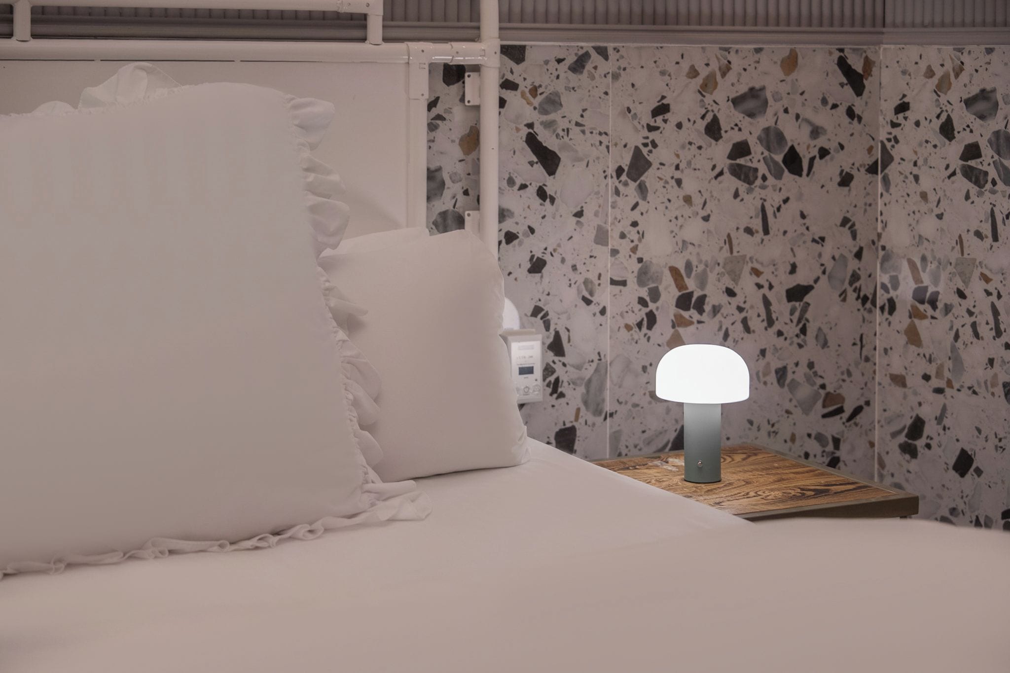 Una cama con ropa de cama blanca y una mesita de noche con lámpara.