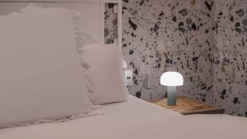 Una cama con ropa de cama blanca y una mesita de noche con lámpara.