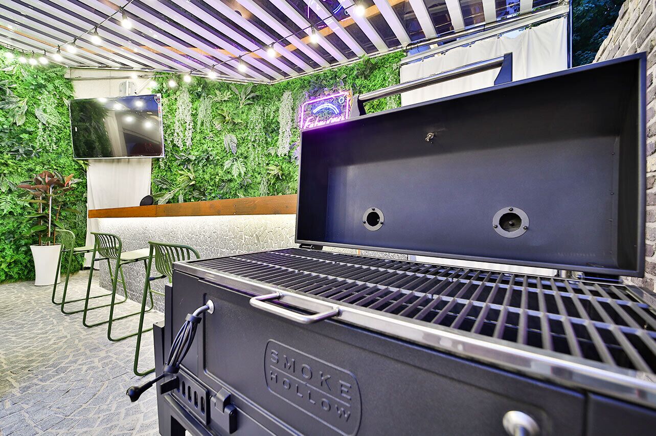 A black outdoor grill with two grill vents, a handle, and a brand name.