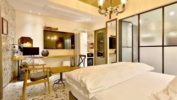 Une chambre d’hôtel avec un lit, un bureau, une chaise et un grand miroir.