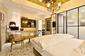 A hotel room with a bed, desk, chair, and a large mirror.