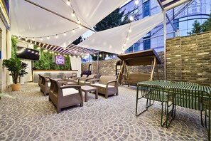 An outdoor seating area with wicker furniture, a flat-screen TV, and string lights. - February Hotel Sungseo (Daegu)