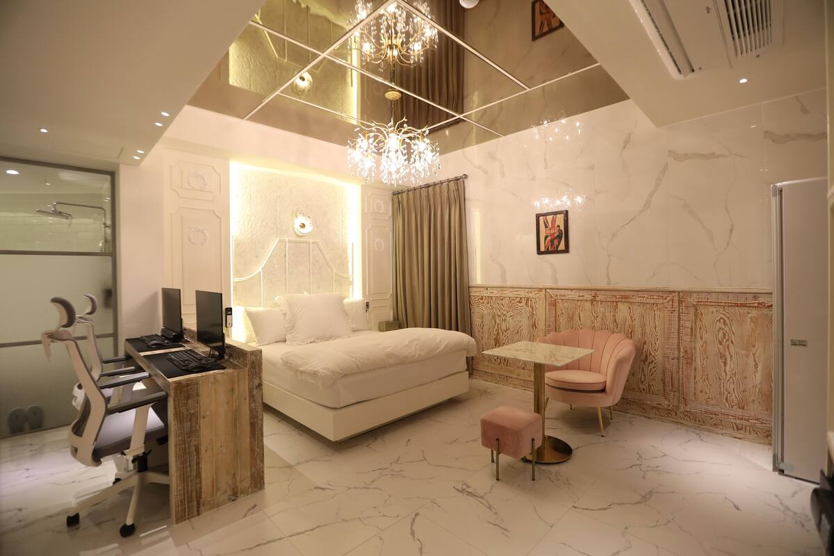 A modern bedroom with a bed, desk, chair, and a small table.