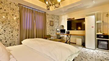 Ein Hotelzimmer mit einem Bett, einem Schreibtisch mit Computer, einem Fernseher und einer Minibar.