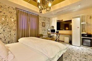 A hotel room with a bed, a desk with a computer, a television, and a minibar. - February Hotel Sungseo (Daegu)