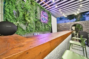 A bar area with a wooden counter, green chairs, a neon sign, and a brick wall. - February Hotel Sungseo (Daegu)