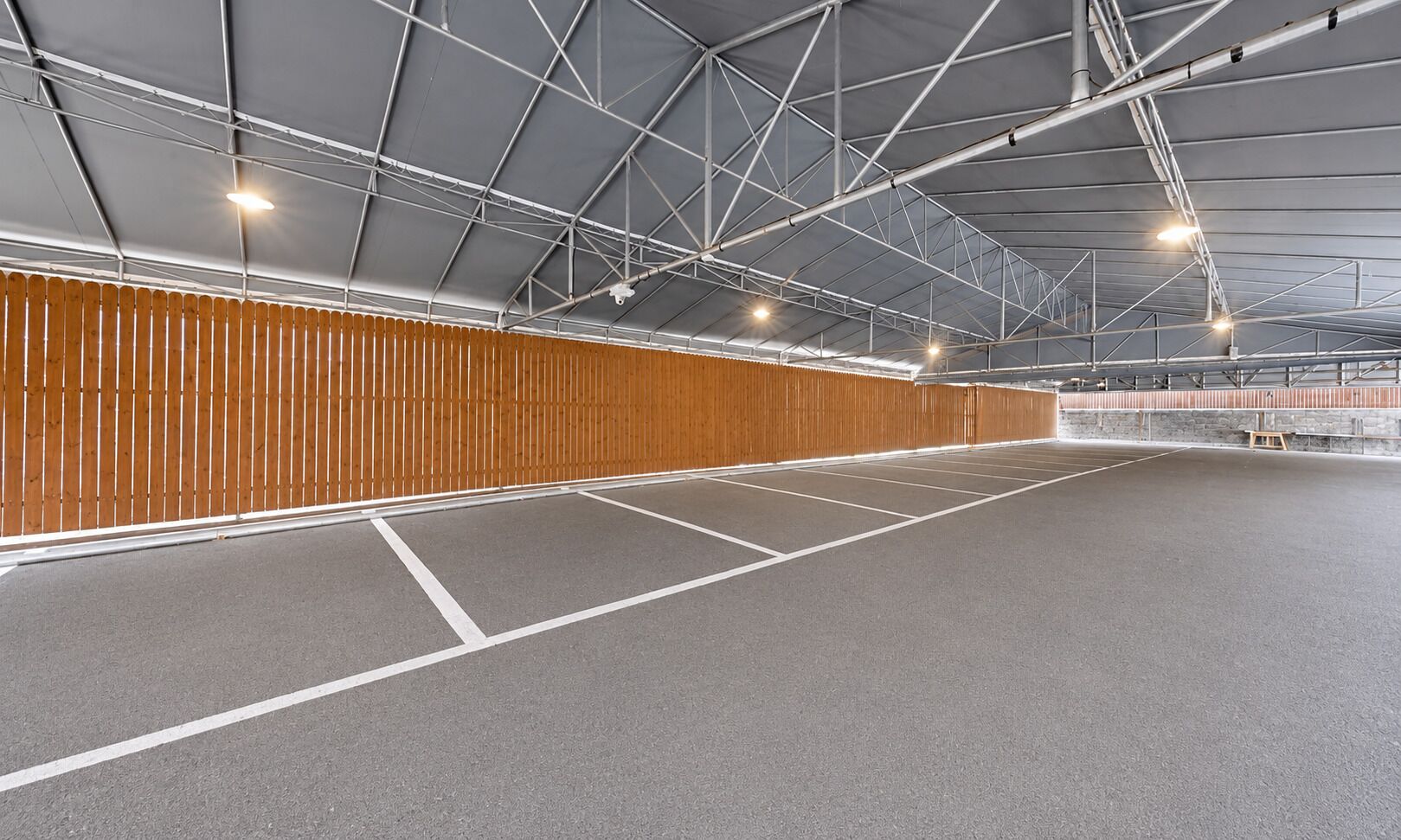 An indoor sports facility with a high ceiling, metal beams, and a wooden wall.