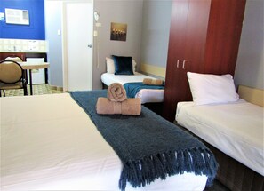 Ein Hotelzimmer mit einem großen Bett, einem kleineren Bett, einem Schreibtisch und einem Stuhl.