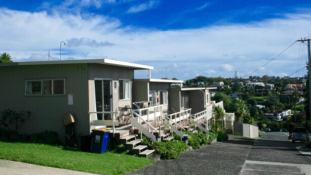 A row of single-story buildings with a small porch and steps leading to the entrance. - Sea Vista Apartments (Auckland)