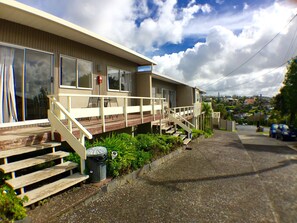 A single-story mobile home with a wooden deck, a small porch, and a front staircase.