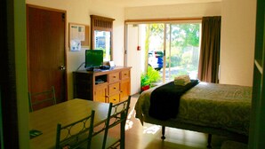 A hotel room with a bed, a desk, a television, and a view of the outdoors. - Sea Vista Apartments (Auckland)