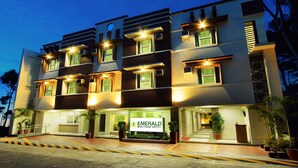 A multi-story hotel with a modern design, featuring balconies and a well-lit entrance. - Emerald Boutique Hotel (Legazpi)