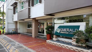 L’entrée d’un hôtel, avec une enseigne indiquant « Emerald Boutique Hotel ».
