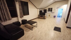 A compact living space with a sofa, a small table, a TV, and a kitchenette.