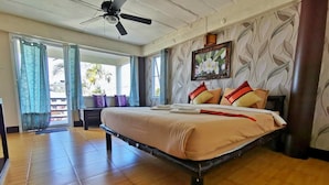 A bedroom with a bed, a ceiling fan, a window with curtains, and a painting on the wall.