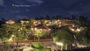 A resort with multiple buildings, outdoor seating, and well-lit pathways.