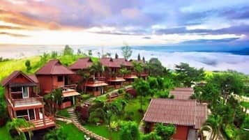 A resort with multiple wooden buildings, some with balconies, surrounded by lush greenery and overlooking a body of water.