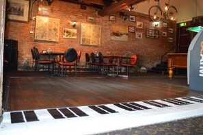 Ein Restaurant mit Backsteinwänden, Holzböden und einem Klavier im Vordergrund.