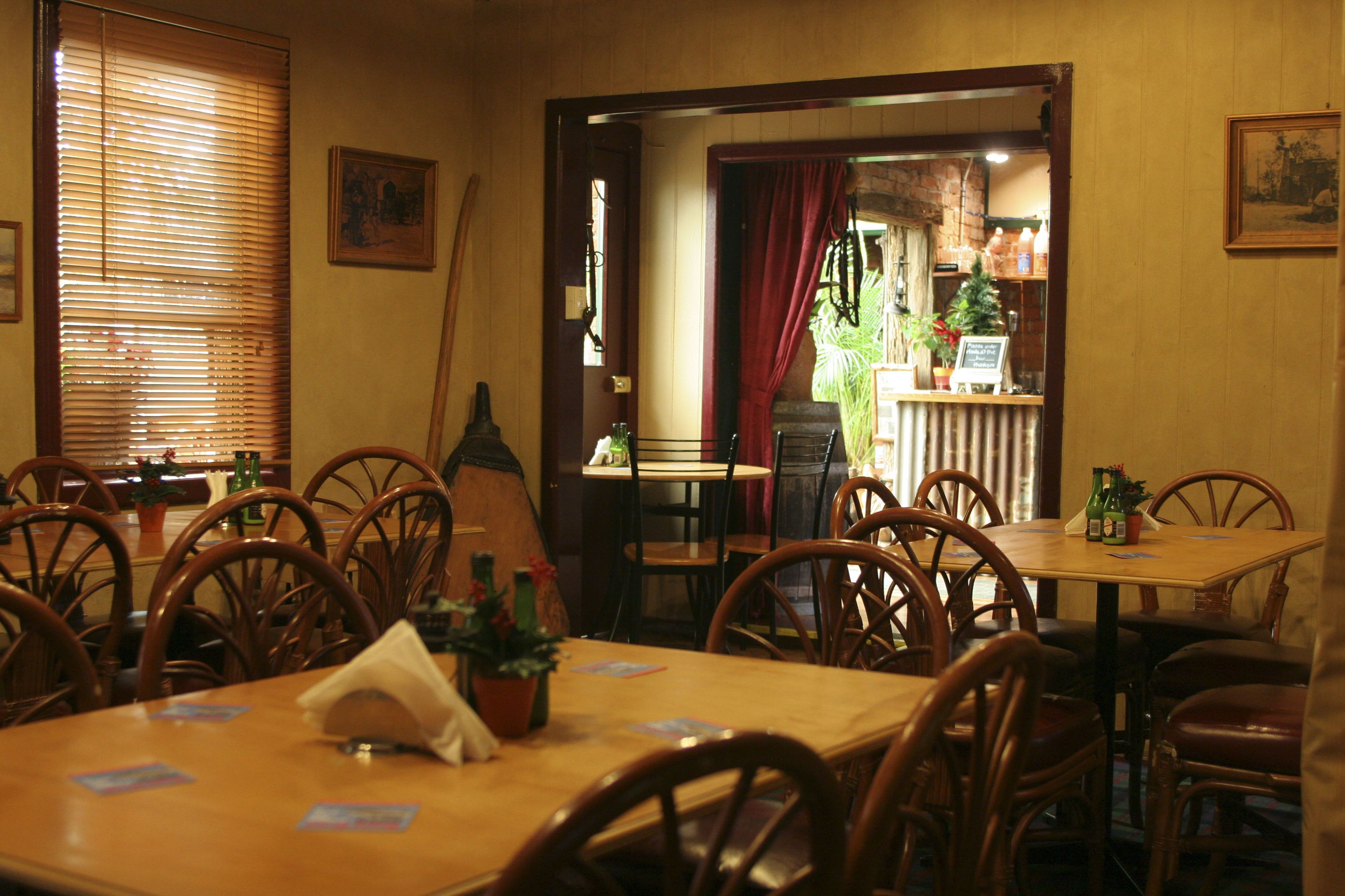 A dining area with wooden tables and chairs, a potted plant, and a sign on the wall.