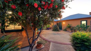 A house with a curved driveway, a small tree, and a patio area with outdoor furniture.