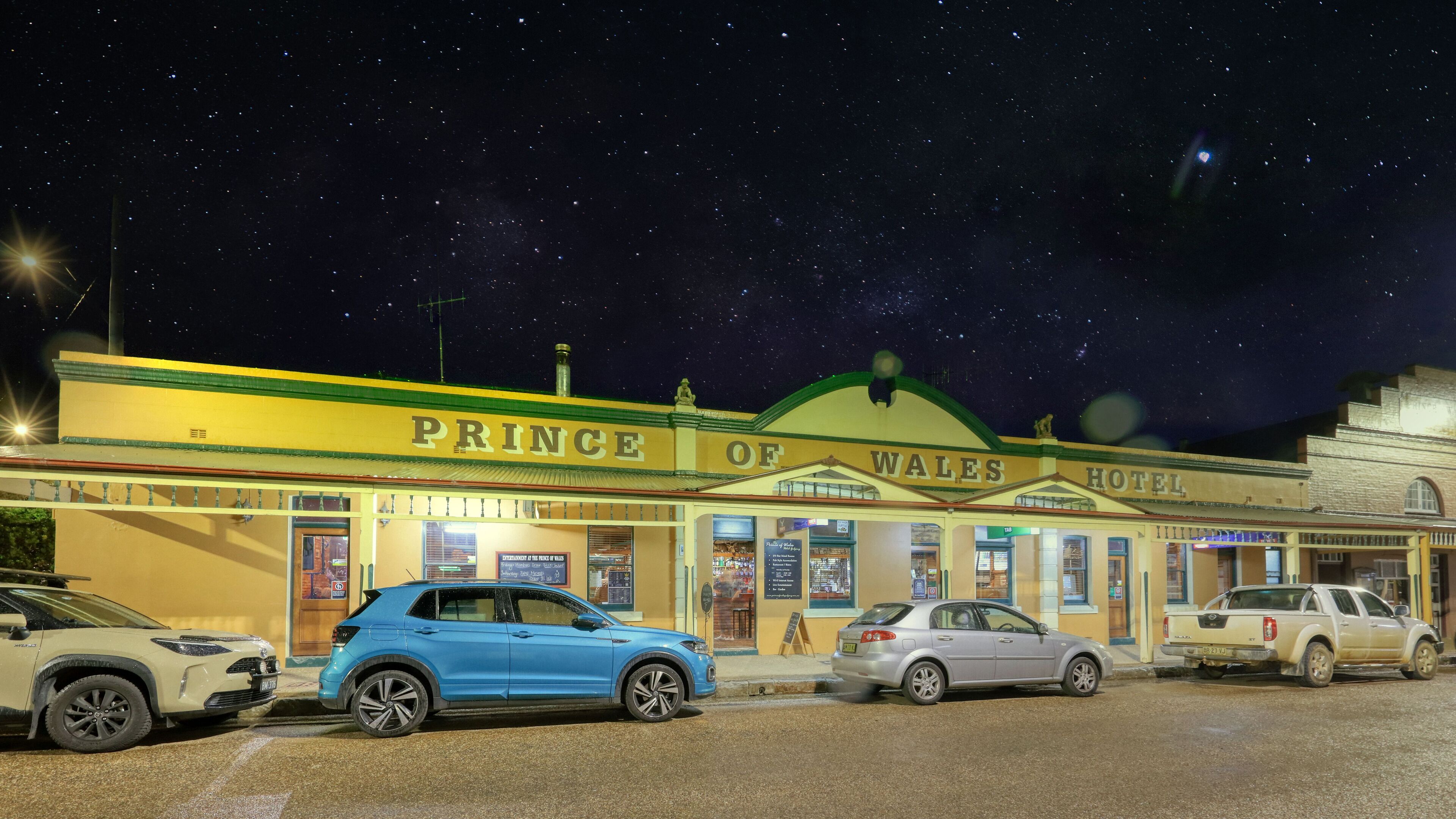 The exterior of the Prince of Wales Hotel with a clear view of the entrance, signage, and parked cars.