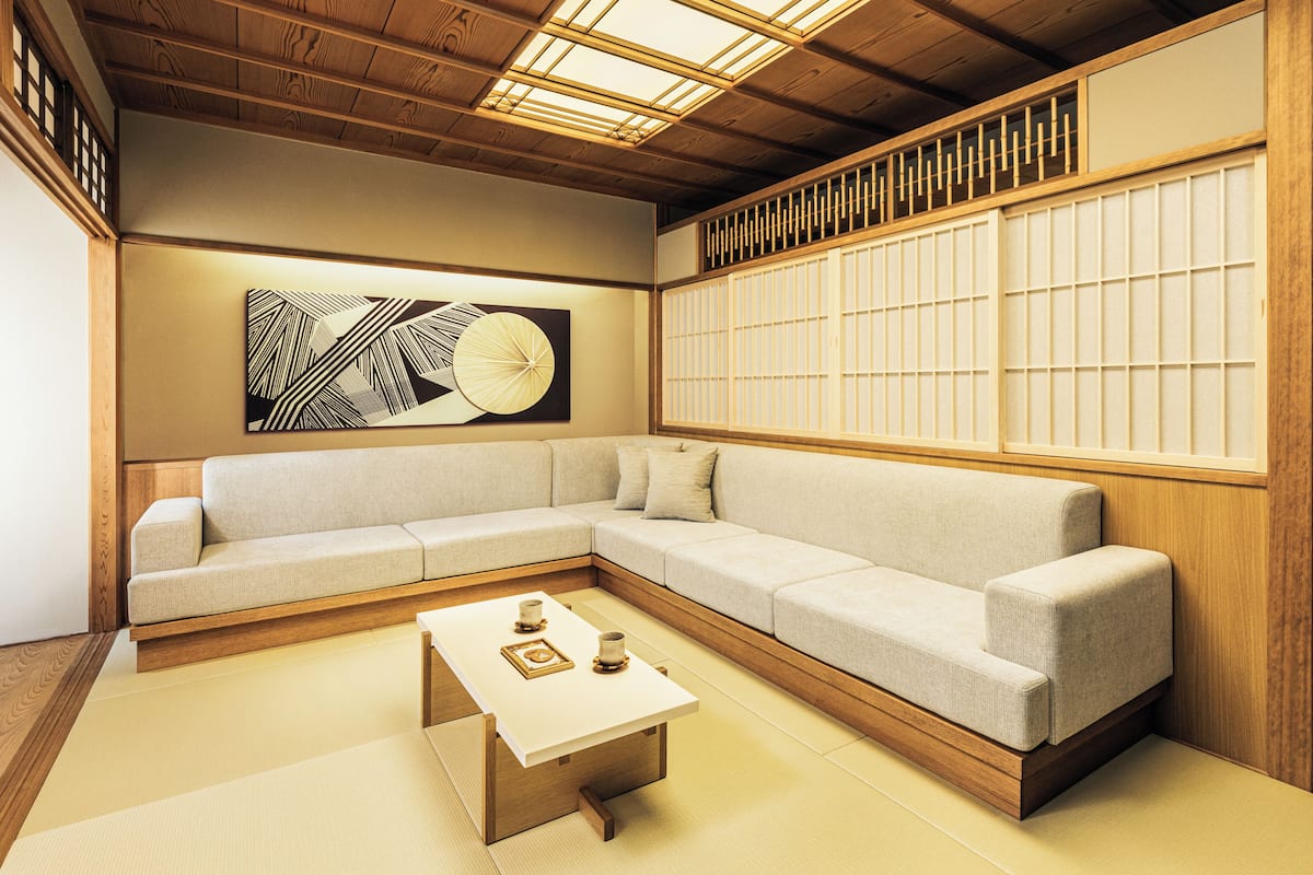 A modern living room with a sectional sofa, a coffee table, and a large abstract painting on the wall.