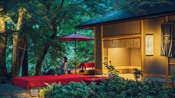 A traditional Japanese-style room with tatami flooring, a low table, and a red umbrella.